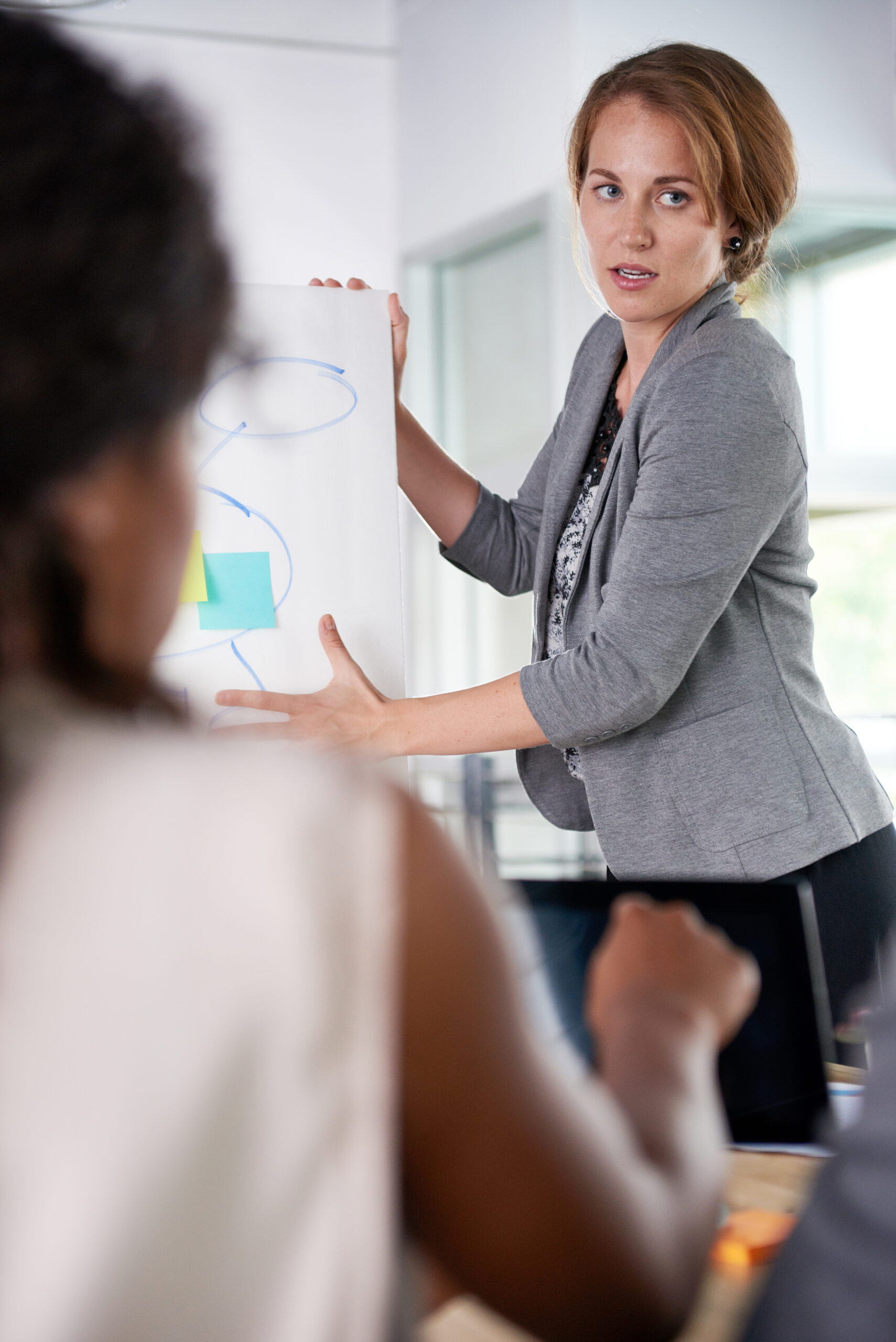 Een vrouw geeft een presentatie aan een team, symbool voor samenwerking en effectieve communicatie.