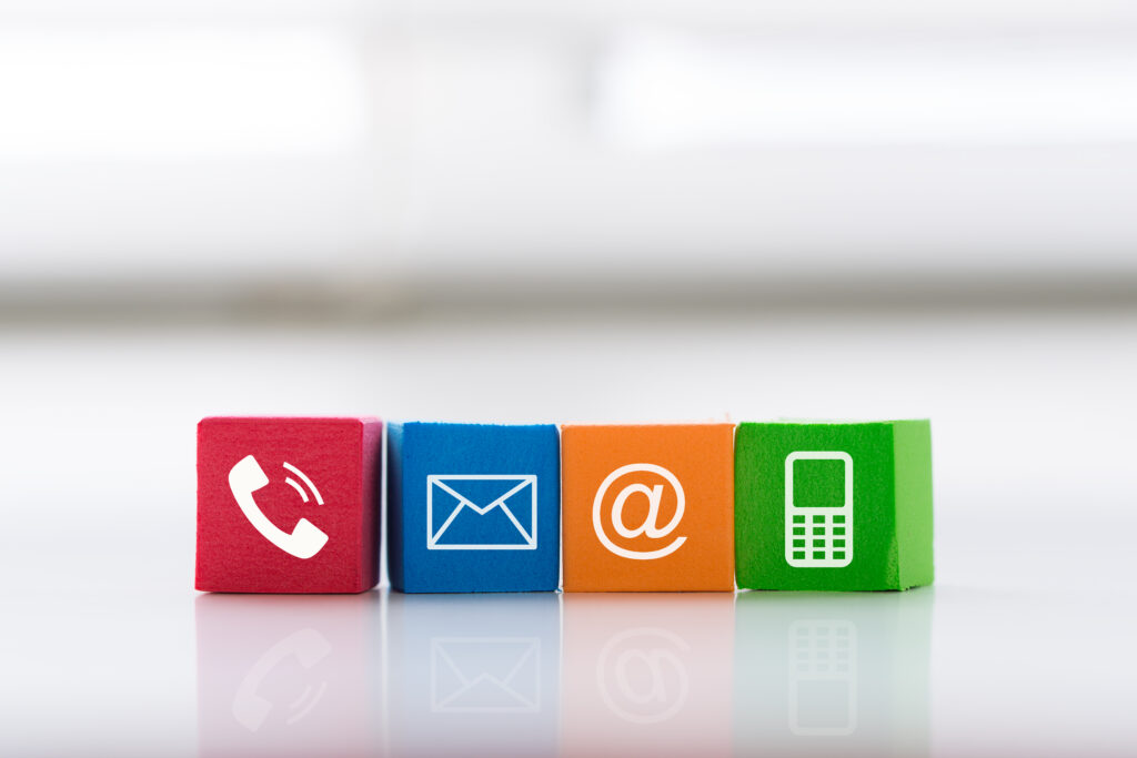 Kleurige blokken met contacticonen: telefoon, envelop, e-mail en mobiele telefoon – symbool voor contactmogelijkheden via Wijwerken.nu.